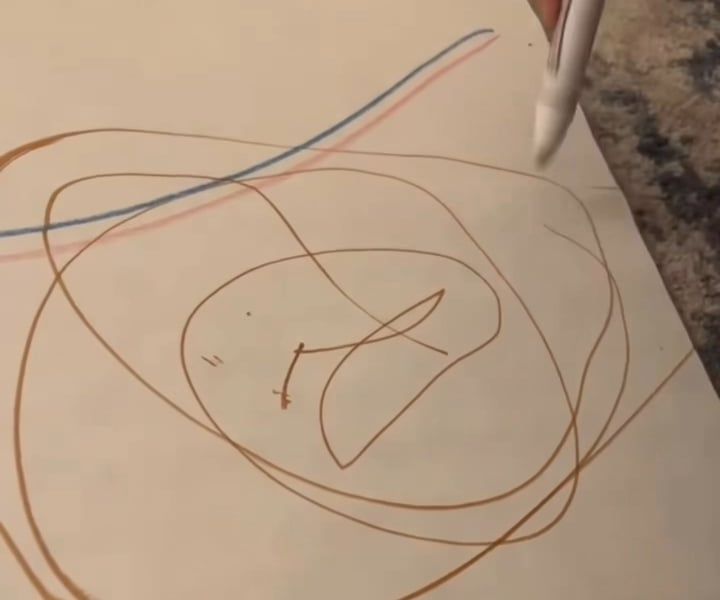 Brown marker loops circling a small mark, crossed by a blue line and a pink line, with a marker at the paper's edge.